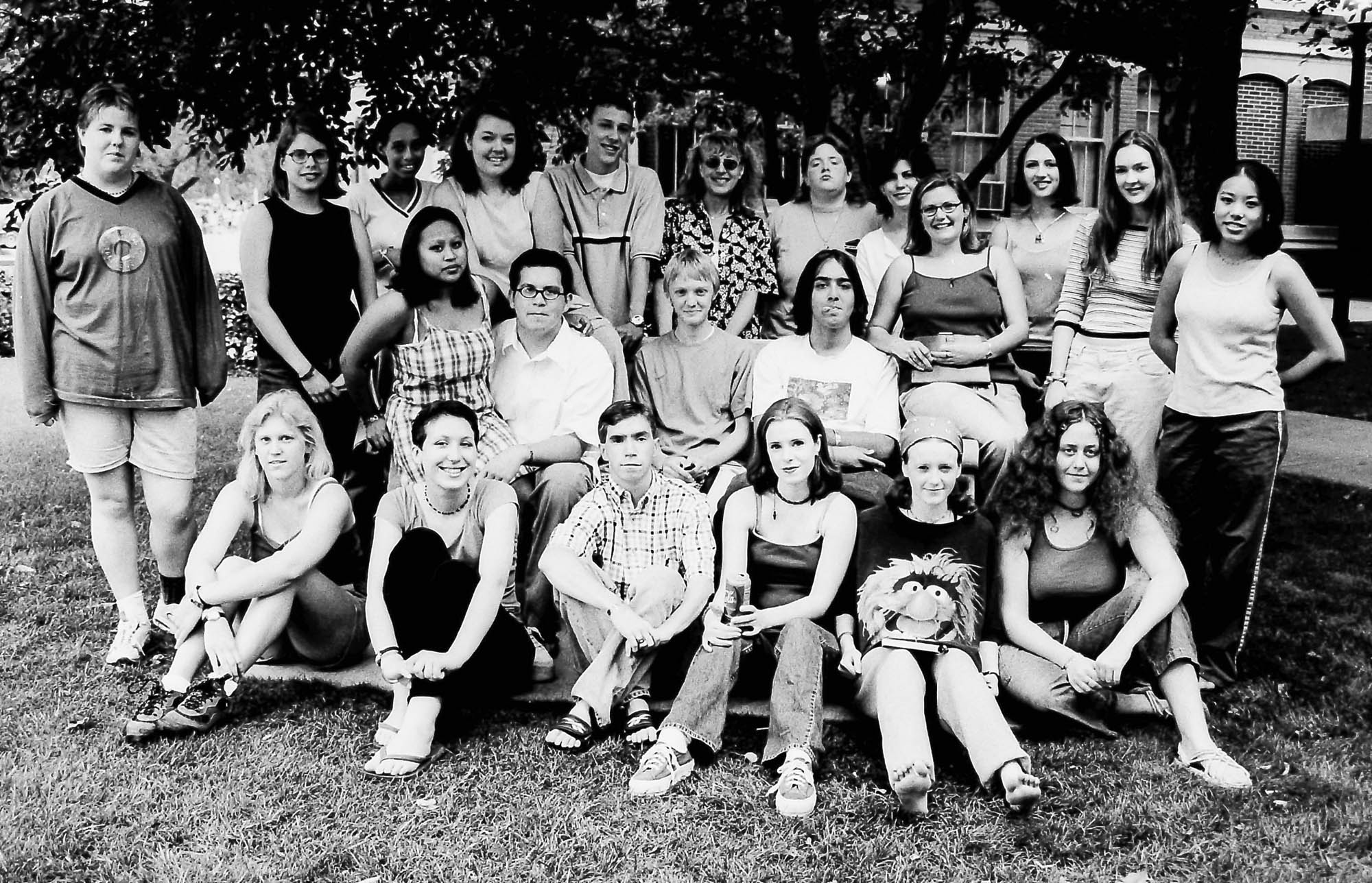 A vintage black-and-white photo depicts a group of teenagers standing outdoors