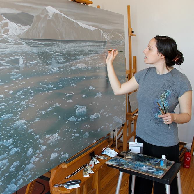 A person stands painting a glacial scene on a large canvas
